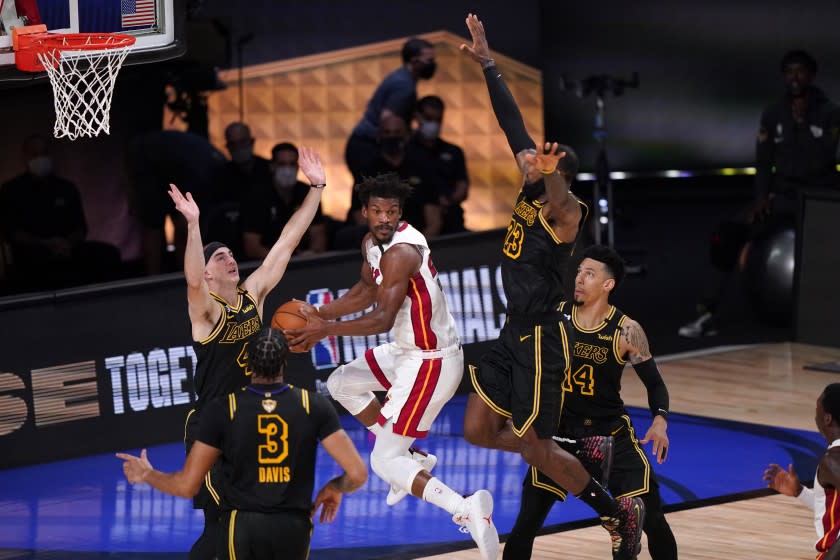 Miami's Jimmy Butler looks to pass as several Lakers, including Anthony Davis (3) and LeBron James (23), defend Oct. 2, 2020.