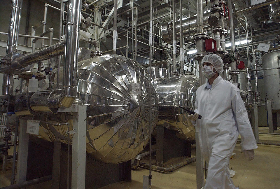 FILE - In this March 30, 2005 file photo, an Iranian security official in protective clothing walks through part of the Uranium Conversion Facility just outside the Iranian city of Isfahan. Iran threatened Wednesday, May 8, 2019, to resume higher enrichment of uranium in 60 days if world powers fail to negotiate new terms for its 2015 nuclear deal, an agreement that capped over a decade of hostility between Tehran and the West over its atomic program. (AP Photo/Vahid Salemi, File)