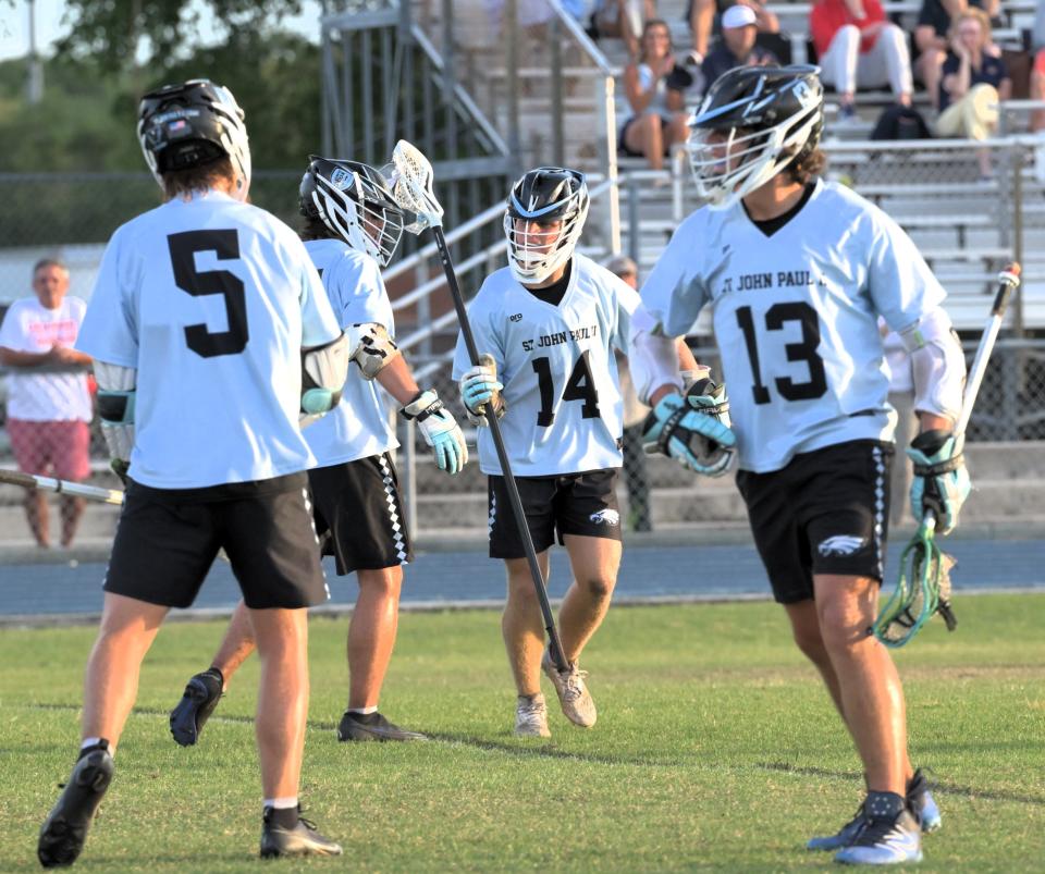 St. John Paul II's Graham McCleneghen celebrates with teammates after a goal scored during Tuesday's district final against Oxbridge Academy on April 16, 2024.