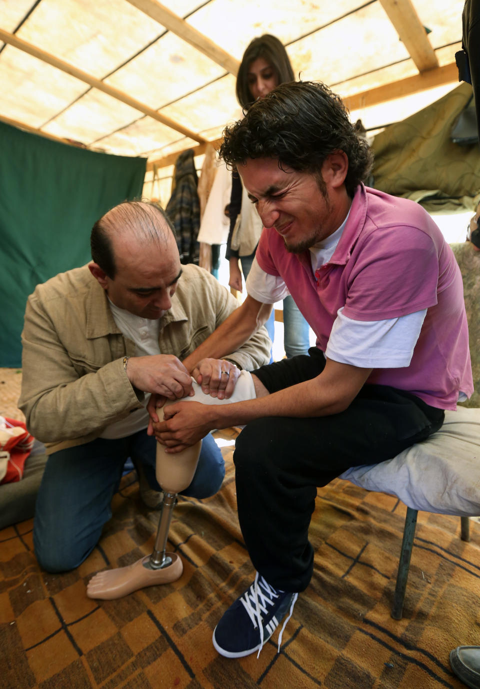 In this Thursday, March. 27, 2014 photo, Mustafa Ahmad, right, a 19-year-old who lost his leg in his hometown of Deir Hafer in Aleppo province in November 2011 when government warplanes bombed his neighborhood, is fitted with a prosthetic leg by a Lebanese prothesis supplier, right, at the Syrian refugee camp in Jib Janine, in the Bekaa valley Lebanon. Syria’s civil war, which entered its fourth year last month, has killed more than 150,000 people. An often overlooked figure is the number of wounded more than 500,000, according to the International Committee of the Red Cross. An untold number of those, there’s no reliable estimate even, have suffered traumatic injuries that have left them physically handicapped. (AP Photo/Bilal Hussein)