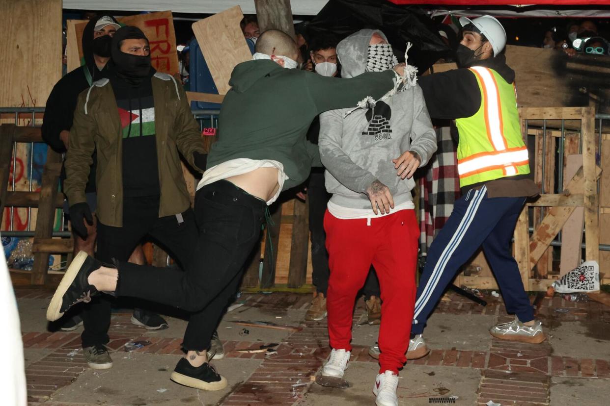 A masked man punches a pro-Palestinian protester.