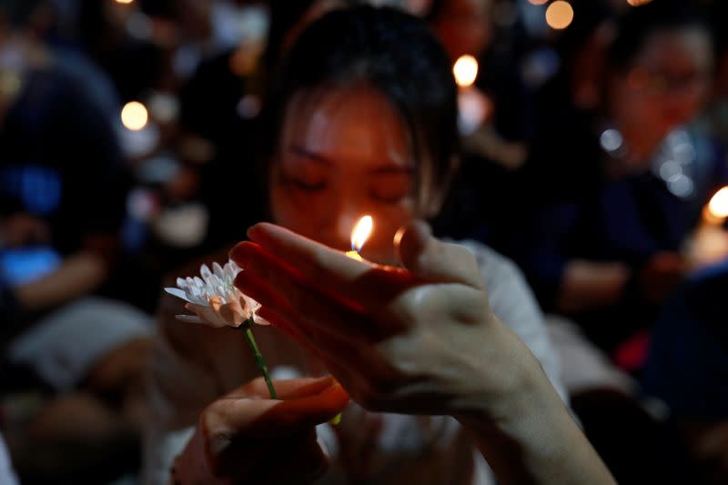 eA woman holds a candle light as she prays for victims who died in mass shooting, involving a Thai soldier on a shooting rampage, in Nakhon Ratchasima