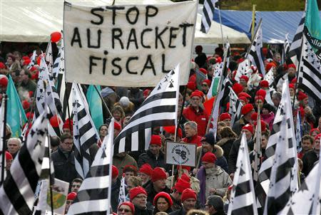 Protesters wearing red caps, the symbol of protest in Brittany and waving Breton regional flags, take part in a demonstration to maintain jobs in the region and against an "ecotax" on commercial trucks, in Carhaix, western France, November 30, 2013. REUTERS/Mal Langsdon