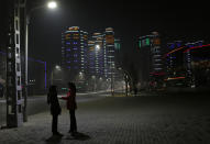 In this Tuesday Feb. 25, 2014 photo, North Korean women chat in a street near a residential complex which is lit at night in Pyongyang, North Korea. (AP Photo/Vincent Yu)