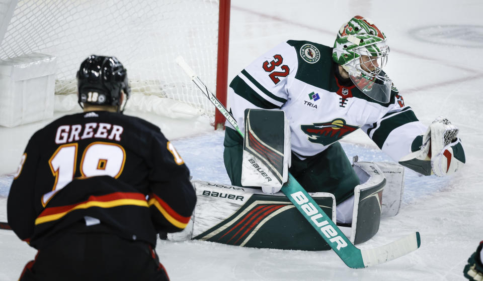 Minnesota Wild goalie Filip Gustavsson, right, grabs the puck as Calgary Flames forward A.J. Greer watches during the third period of an NHL hockey game in Calgary, Alberta, Tuesday, Dec. 5, 2023. (Jeff McIntosh/The Canadian Press via AP)