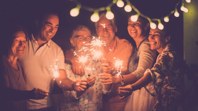 group of caucasian people friends with different ages celebrate together a birthday or new year eve by night outdoor at home.