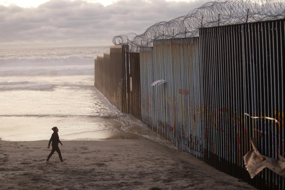 A woman walks on the beach next to the border wall topped with razor wire in Tijuana, Mexico on Jan. 9, 2019. (Photo: Gregory Bull/AP)