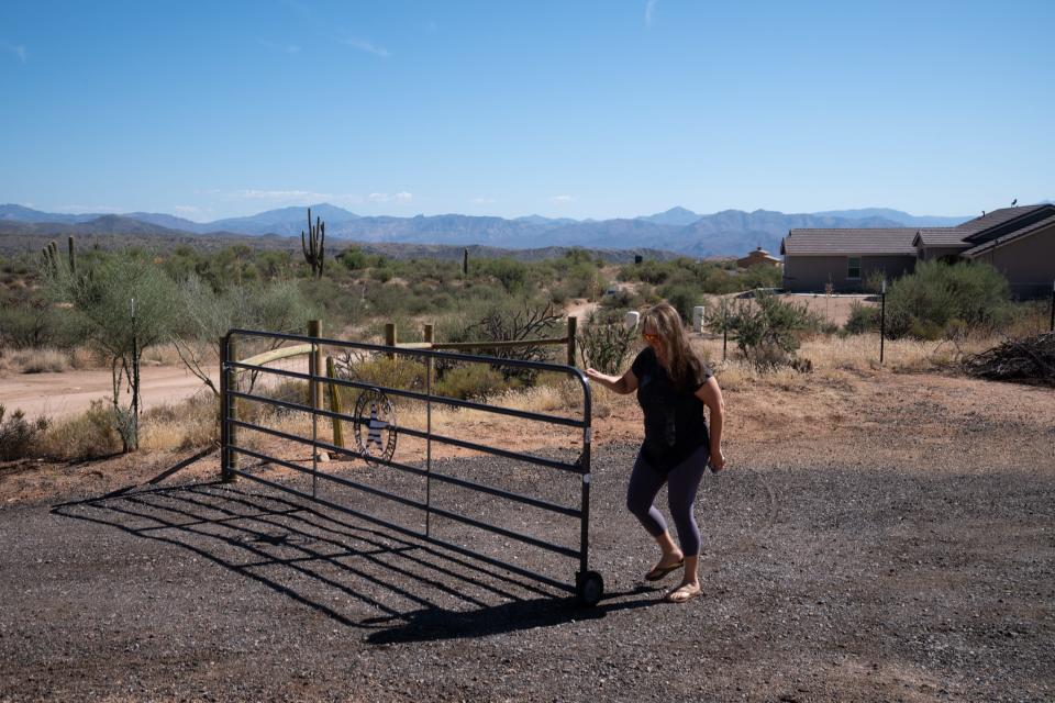 Wendy Bobbitt closes the gate, October 10, 2023, at her home in the Rio Verde Foothills, Arizona.