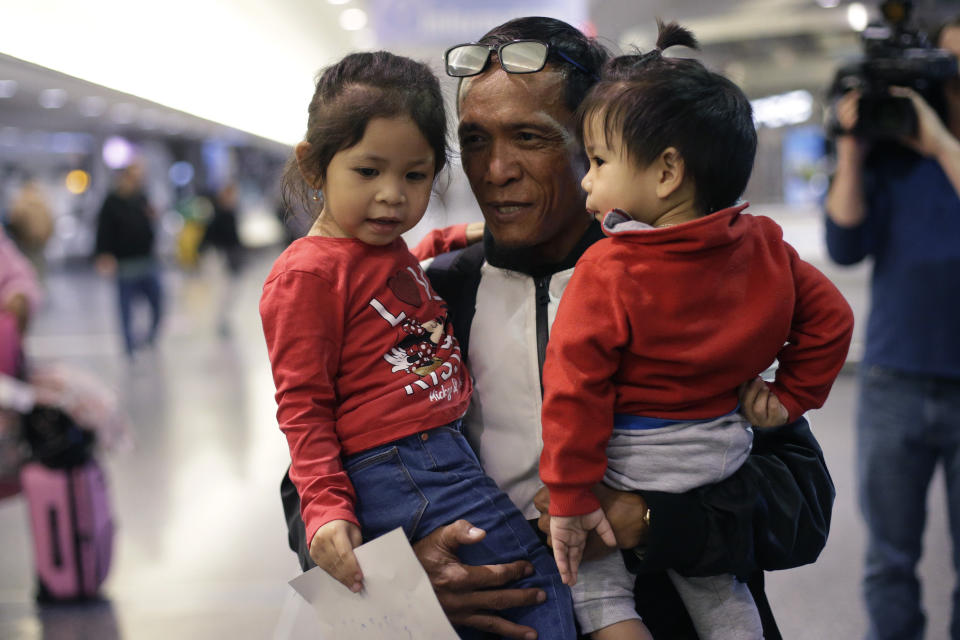 Thy Chea, of Lowell, Mass., center, originally of Cambodia, holds his daughter, left, and son, right, on his arrival at Boston's Logan Airport, Wednesday, Feb. 26, 2020, after getting his green card reinstated last year. Chea is the fourth Cambodian refugee to be allowed back into the country after being deported, and just the first on the East Coast, according to Asian American organizations that have been fighting increased deportations of Southeast Asians under President Donald Trump. Chea met his son for the first time at the airport. (AP Photo/Steven Senne)