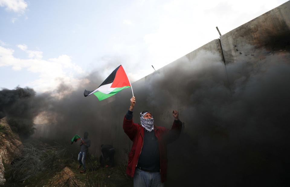 Protester holds a Palestinian flag during clashes with Israeli troops