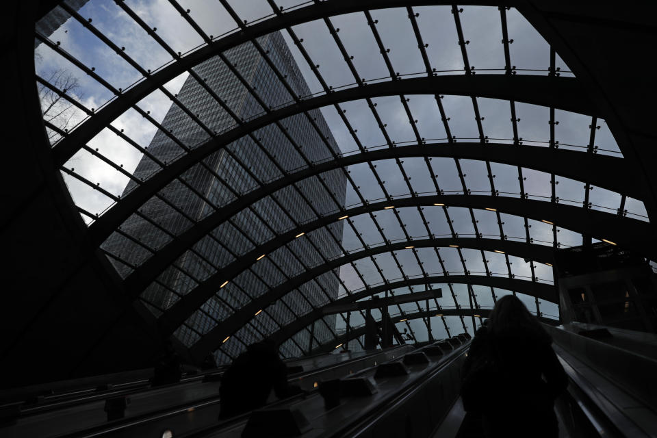 People use the escalator as they exit Canary Wharf underground station, with the JP Morgan building above them at left, in London, Thursday, March 25, 2021. (AP Photo/Alastair Grant)