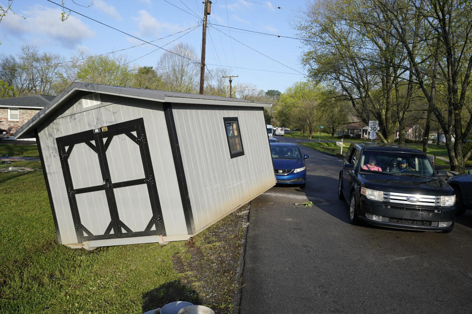 A vehicle passes a utility building that was carried onto a street by floodwaters Sunday, March 28, 2021, in Nashville, Tenn. Heavy rain across Tennessee flooded homes and roads as a line of severe storms crossed the state. (AP Photo/Mark Humphrey)