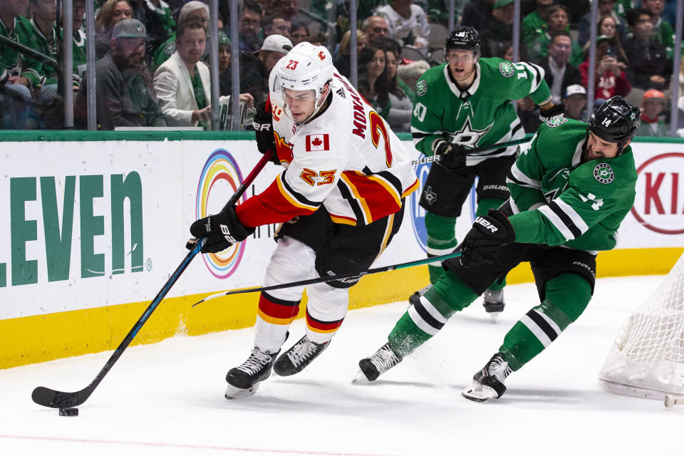 Calgary Flames center Sean Monahan (23) skates with the puck behind the net as Dallas Stars left wing Jamie Benn (14) defends during the first period of an NHL hockey game, Sunday, Dec. 22, 2019, in Dallas. (AP Photo/Sam Hodde)