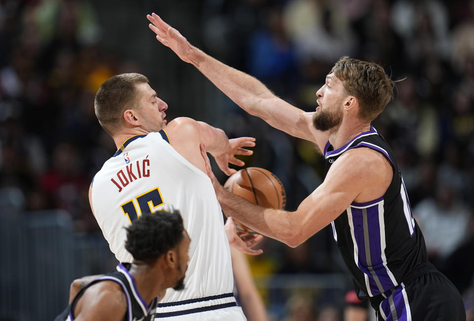 Denver Nuggets center Nikola Jokic, left, passes the ball as Sacramento Kings forward Domantas Sabonis defends during the first half of an NBA basketball game Wednesday, Feb. 28, 2024, in Denver. (AP Photo/David Zalubowski)