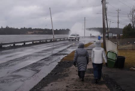 Pedestrians walk along a closed section of road as storm surge from the Atlantic Ocean causes waves to crash over the break wall during Storm Grayson in Halifax, Nova Scotia, Canada January 5, 2018. REUTERS/Darren Calabrese