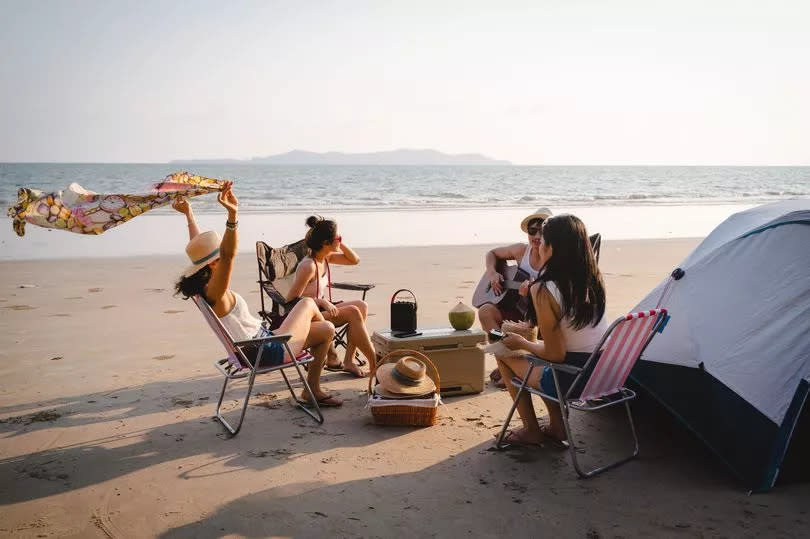 Group of friends having fun enjoying beach camping in summer