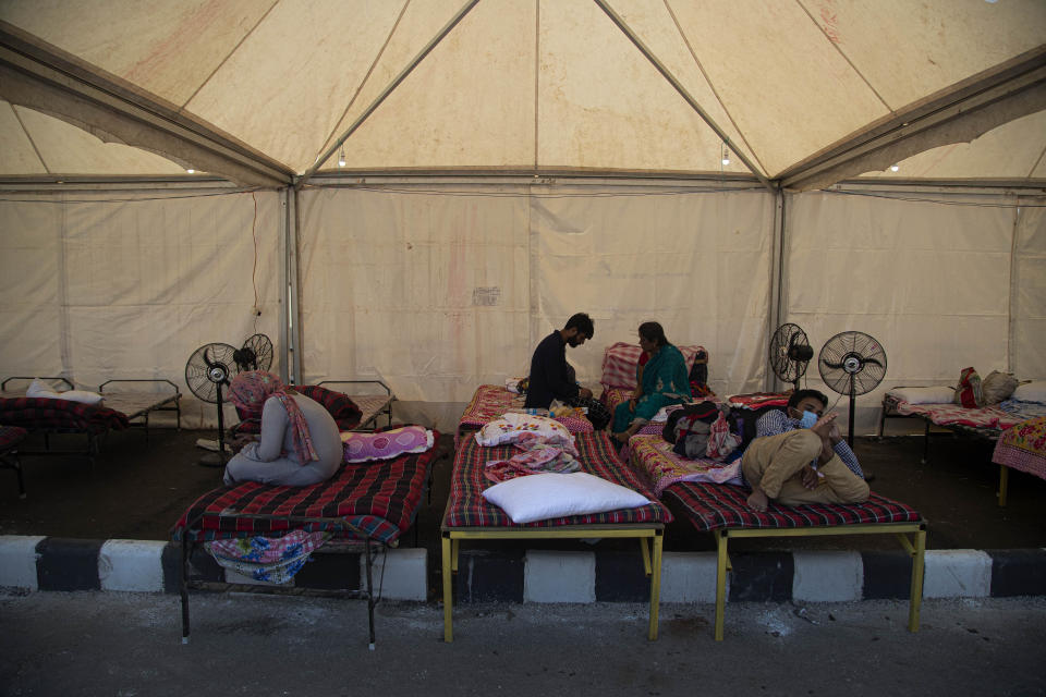 Migrant workers rest inside a tent before traveling in a Shramik train arranged to transport them to their home states, at a railway station in Gauhati, India, Thursday, May 28, 2020. Rural villages across India are seeing an increase in cases with the return of hundreds of thousands of migrant workers who left cities and towns where they were abandoned by their employers after having toiled for years building homes and roads. India sees no respite from the coronavirus caseload at a time when the two-month-old lockdown across the country is set to end on Sunday. (AP Photo/Anupam Nath)