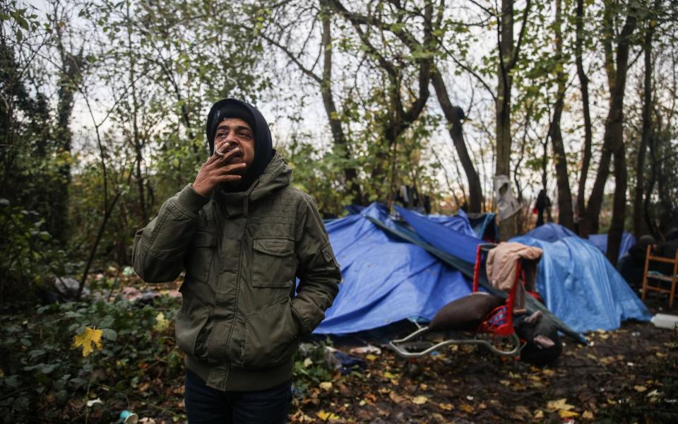 Ali, 36-year-old Tunisian migrant, smokes a cigarette next to his tent at an unorganised camp in Calais - Mohammed Badra/EPA-EFE/Shutterstock