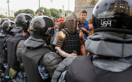 A man wearing a knight outfit walks past police officers blocking a street during a rally against planned increases to the nationwide pension age in St. Petersburg, Russia September 9, 2018. REUTERS/Anton Vaganov