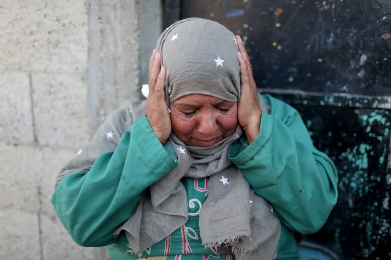 Palestinian woman reacts as she sits outside her home in the southern Gaza Strip