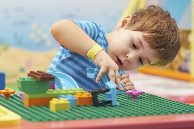 child playing and building with colorful plastic bricks table. Early learning and development.