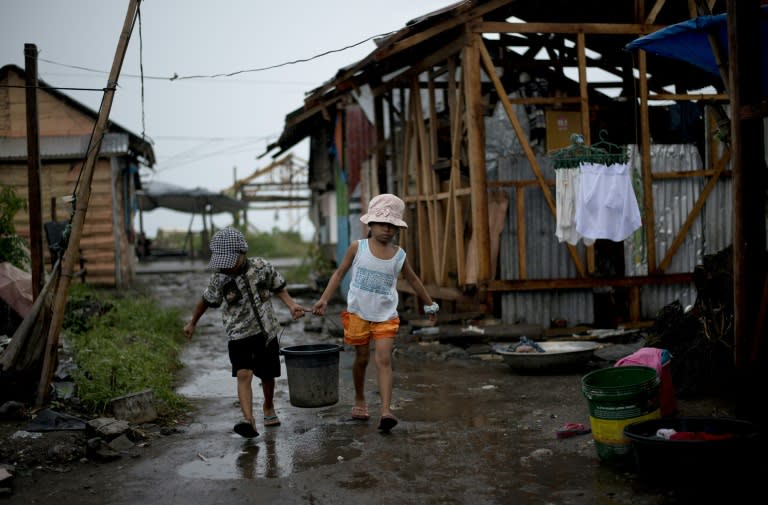 Children carry water on October 14, 2014 at a tent city in Tacloban, which was devastated by Super Typhoon Haiyan in 2013