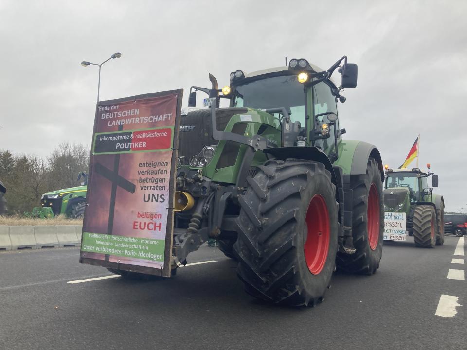 Tractors stand on a road and block it near Ramin, Germany, Friday, Feb. 2, 2024. German lawmakers have approved cuts to fuel subsidies for farmers that prompted angry protests, along with a 2024 budget that the government had to revamp after a court ruling blew a hole in its financial plans. (Christian Johner/dpa via AP)