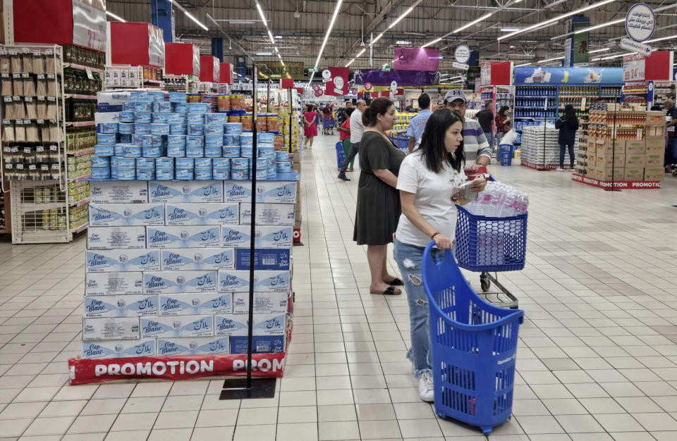 People shop at a supermarket, in Tunis, Tunisia, Monday, Oct. 10, 2022. Sugar, vegetable oil, rice, even bottled water – Tunisians have suffered shortages of multiple staples in recent weeks. And costs are soaring on products still available. (AP Photo/Hassene Dridi)