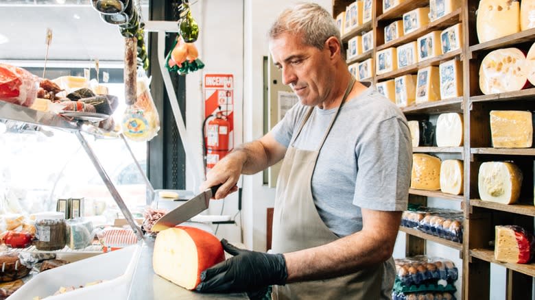A cheesemonger cutting a block of cheese