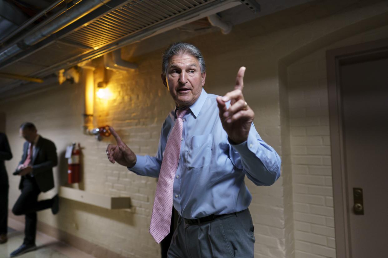 Sen. Joe Manchin, D-W.Va., a key infrastructure negotiator, signals to his staff as he works behind closed doors with other Democrats in a basement room at the Capitol in Washington, Wednesday, June 16. 