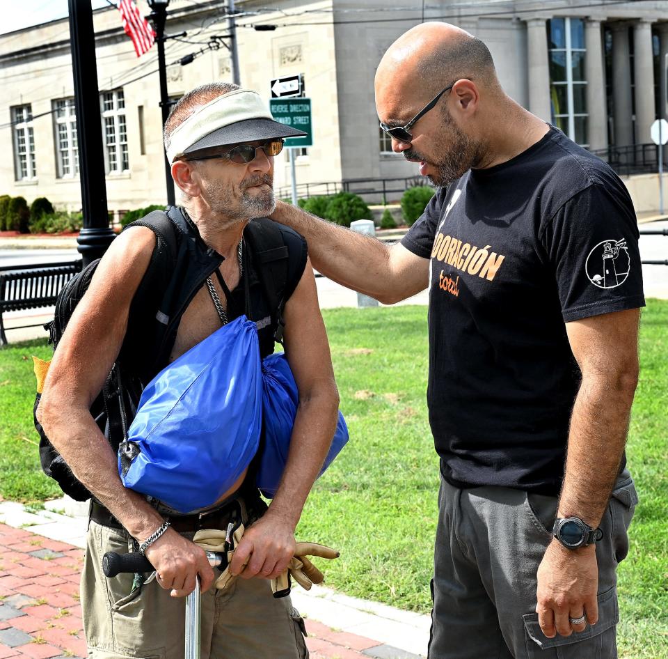 Justo Rosario, right, a pastor of Light of Hope Church in Framingham, prays with Stanley Galazka, a Framingham man who said he has been homeless, on the Framingham Downtown Common, Sept. 3, 2022. Galazka had just gotten free pizza and a care package during a "Neighborhood Give Back" event that was the brainchild of Cheniel Garcia of Framingham, an aspiring hip-hop artist who turned his life around after spending time in prison.