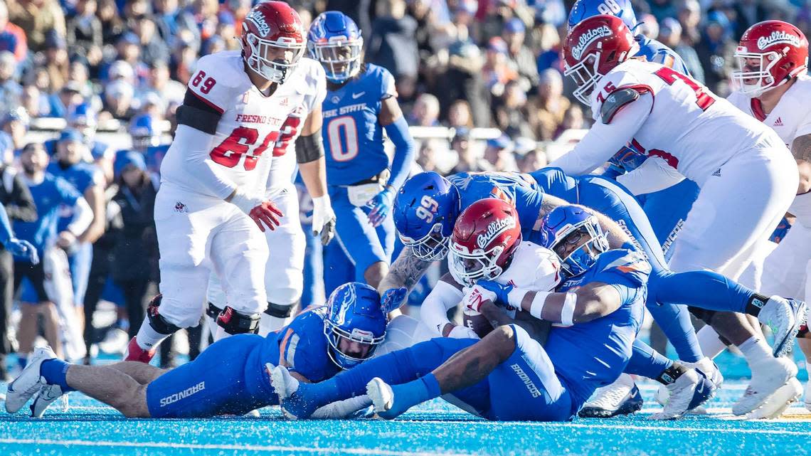 Boise State linebacker DJ Schramm, left, Boise State defensive tackle Scott Matlock, center, and Boise State defensive lineman Cortez Hogans, right, take down Fresno State running back Jordan Mims in the first quarter during the Mountain West Championship game held on Saturday, Dec. 3, 2022 at Albertsons Stadium.
