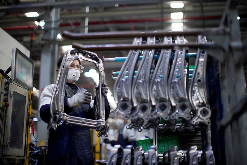 FILE PHOTO: Employee wearing a face mask works on a car seat assembly line at Yanfeng Adient factory in Shanghai