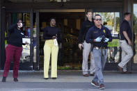 Police officers and Kroger employees exit a Kroger grocery store Friday, Sept. 24, 2021, in Collierville, Tenn. Police say a gunman, who has been identified as a third-party vendor to the store, attacked people Thursday and killed at least one person and wounded others before being found dead of an apparent self-inflicted gunshot wound. (AP Photo/Mark Humphrey)