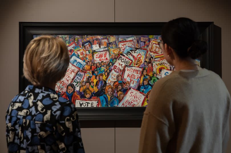 People look at a painting in the new Last Cage Down exhibition at the Mining Art Gallery