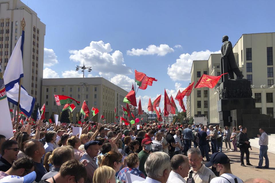 Hundreds of supporters of Belarusian President Alexander Lukashenko with Belarusian State flags gather at Independent Square of Minsk, Belarus, Sunday, Aug. 16, 2020. On Saturday, thousands of demonstrators rallied at the spot in Belarus' capital where a protester died in clashes with police, calling for Lukashenko to resign. (AP Photo/Sergei Grits)