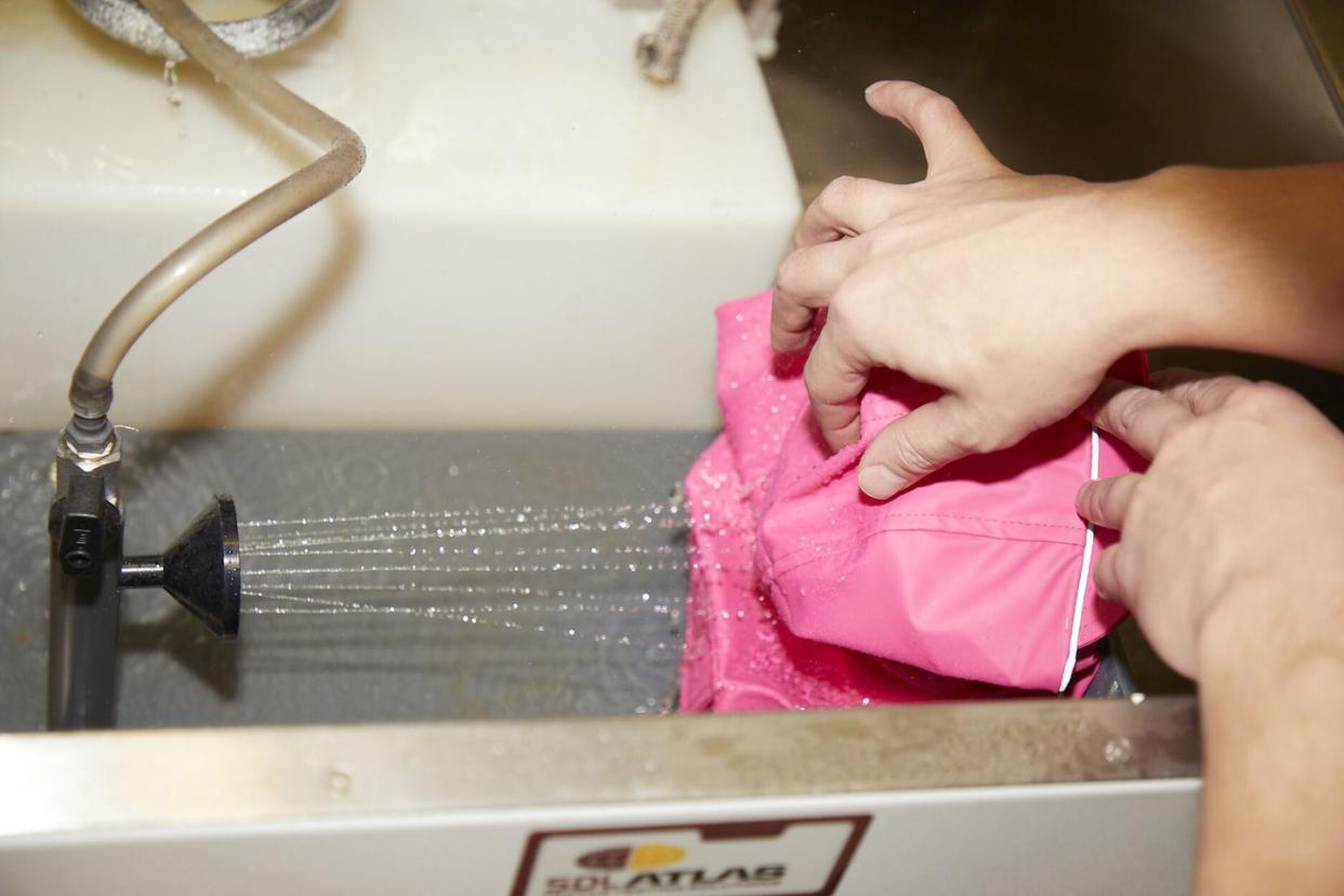 a pink dog jacket being tested for its ability to keep out water, pink jacket in a rain machine at the good housekeeping institute