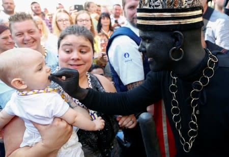 "The Savage", a white performer in a blackface disguise, touches a baby during the festival Ducasse d'Ath in Ath
