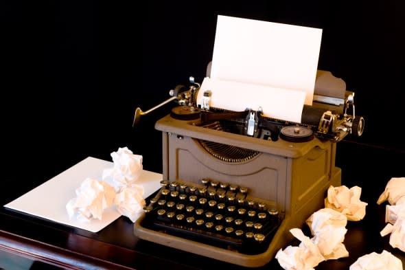 A vaintage typewriter with several wadded up pieces of paper arranged around it.  symbol of writer's block or difficulty with cr