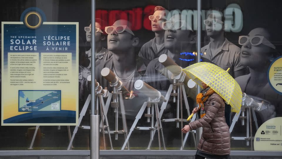 A pedestrian walks past a solar eclipse information board on a rainy day in Toronto on April 3, 2024. Many would-be viewers are worried about bad weather, particularly in points south. - Mert Alper Dervis/Anadolu Agency/Getty Images