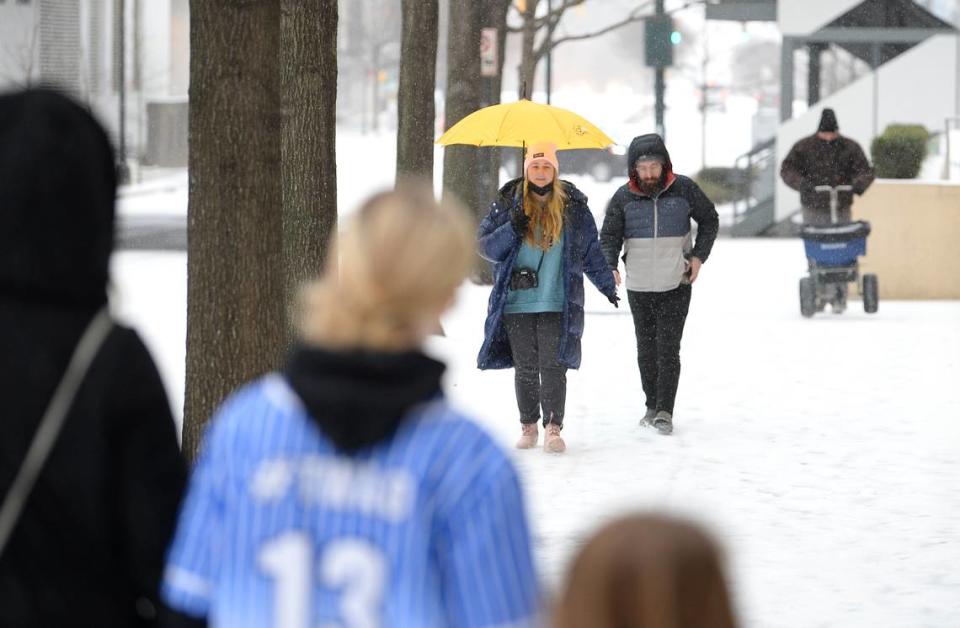 Brooke Gautreaux, left and her husband, Caray, right, walk along Stonewall Street as a wintry mix of rain, sleet and snow fall on Sunday, January 16, 2022.