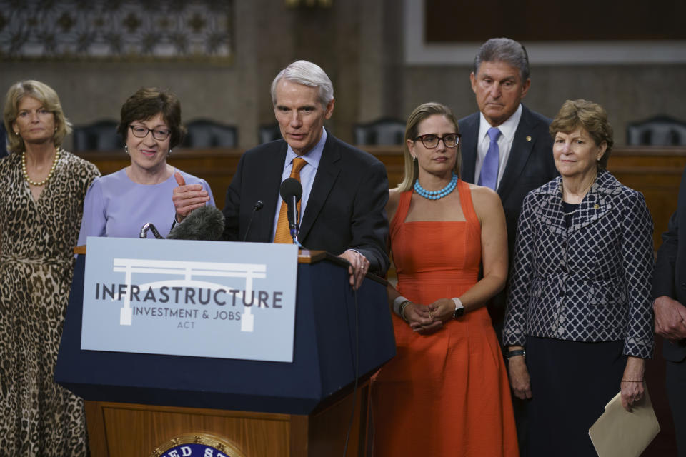 The bipartisan group of Senate negotiators speak to reporters just after a vote to start work on a nearly $1 trillion bipartisan infrastructure package, at the Capitol in Washington, Wednesday, July 28, 2021. From left are Sen. Lisa Murkowski, R-Alaska, Sen. Susan Collins, R-Maine, Sen. Rob Portman, R-Ohio, Sen. Kyrsten Sinema, D-Ariz., Sen. Joe Manchin, D-W.Va., and Sen. Jeanne Shaheen, D-N.H., (AP Photo/J. Scott Applewhite)