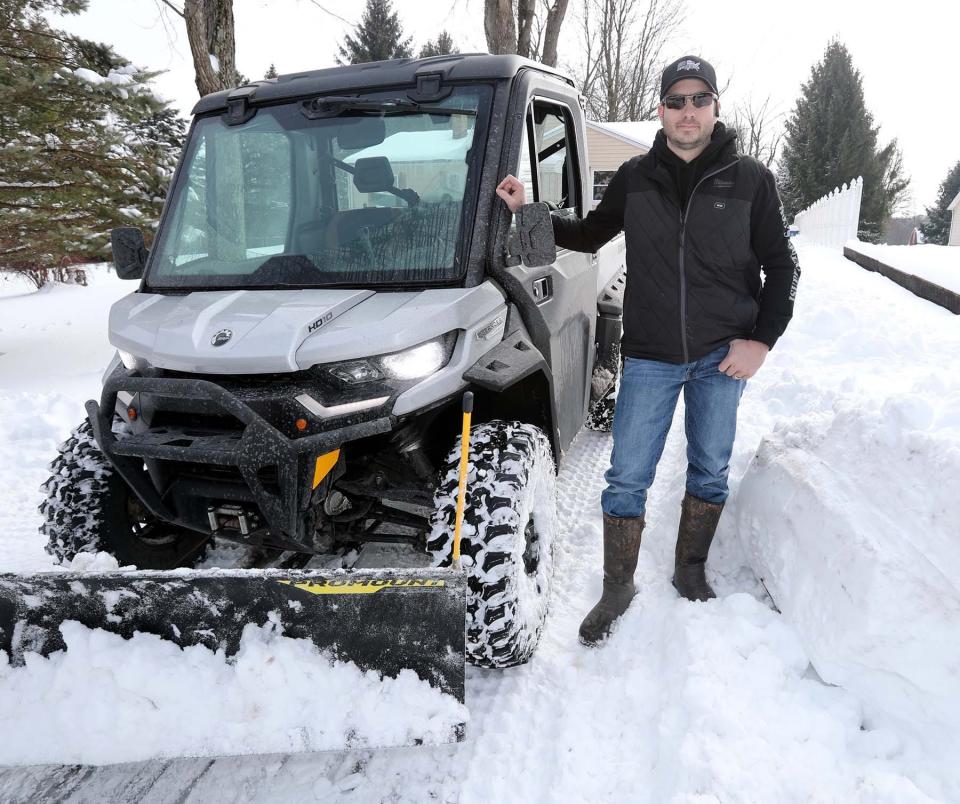 Norton Councilman Doug DeHarpart stands next to his plow in the driveway of a Norton resident on Tuesday. He has plowed several driveways of Norton residents.