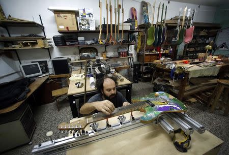 Argentine luthier Ezequiel Galasso works on a guitar he made out of skateboards at his workshop in Buenos Aires October 17, 2014. REUTERS/Marcos Brindicci