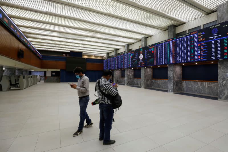 People check their mobile phones as they stand in the trading hall of the Pakistan Stock Exchange after an attack in Karachi