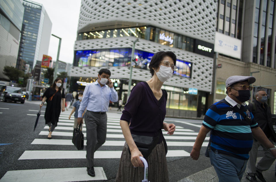 People wearing face masks walk across a traffic intersection in the Ginza shopping district of Tokyo during a state of emergency on Thursday, Sept. 30, 2021. On Friday, Oct. 1, 2021, Japan fully came out of a coronavirus state of emergency for the first time in more than six months as the country starts gradually easing virus measures to help rejuvenate the pandemic-hit economy as the infections slowed.(AP Photo/Hiro Komae)