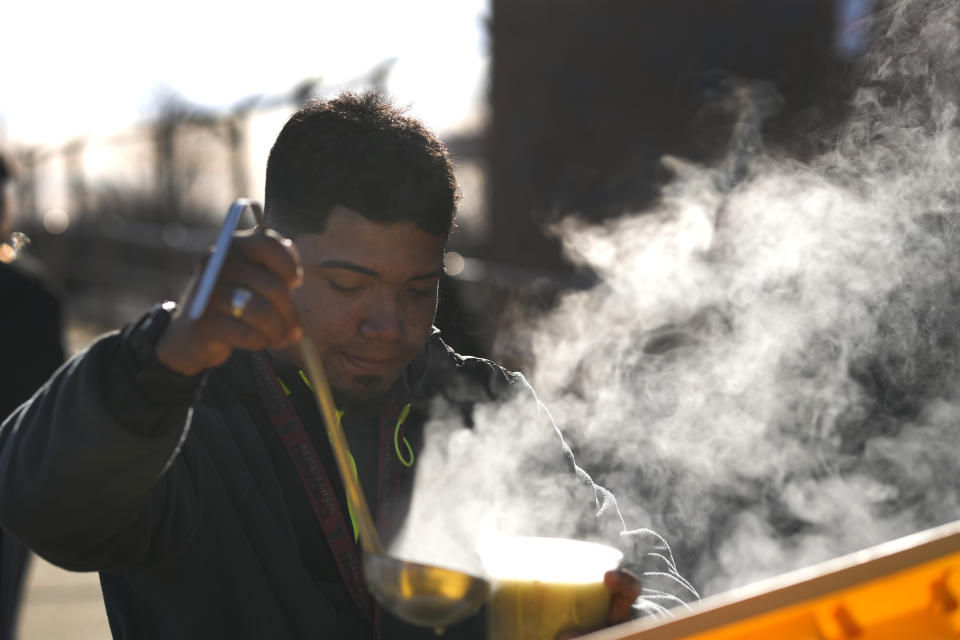 Steam rises in the cold air as a man ladles out soup across the street from an immigrant shelter in the Pilsen neighborhood of Chicago, Tuesday, Dec. 19, 2023. The death of a 5-year-old migrant boy and reported illnesses in other children living at the shelter has raised concerns about the living conditions and medical care provided for asylum-seekers arriving in Chicago. Four more people living in the same shelter — mostly children — were hospitalized with fevers this week. (AP Photo/Charles Rex Arbogast)