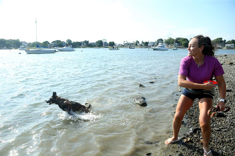 Brianna Mahoney, of Braintree, throws a Frisbee into the water for her dog, Tika, to fetch at Stodder's Neck Park on Thursday, July 28, 2022.