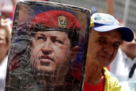 A government supporter holds up a photograph of Venezuela's late President Hugo Chavez during a rally in support of Venezuela's President Nicolas Maduro in Caracas, Venezuela May 22, 2017. REUTERS/Marco Bello