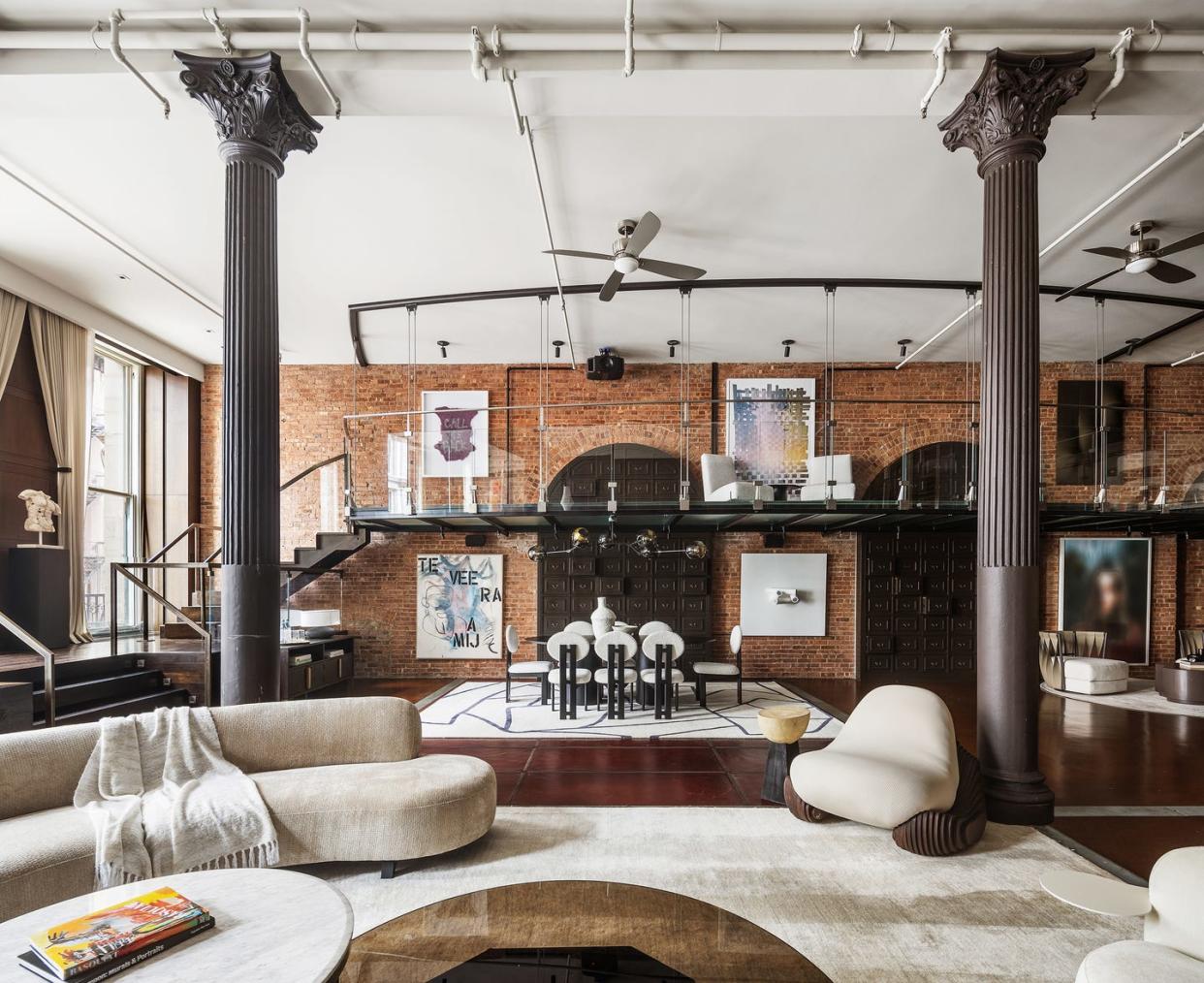 loft apartment in new york, with columns, curvilinear couches, and exposed brick walls